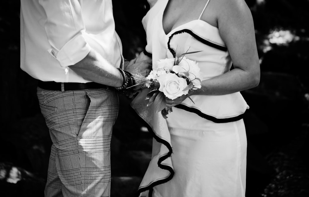 grayscale photography of man and woman holding hand together