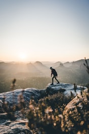 man walking on gray rock mountain during daytime