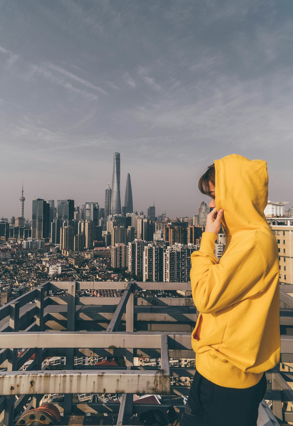 Persona in felpa con cappuccio gialla in piedi su telaio metallico grigio