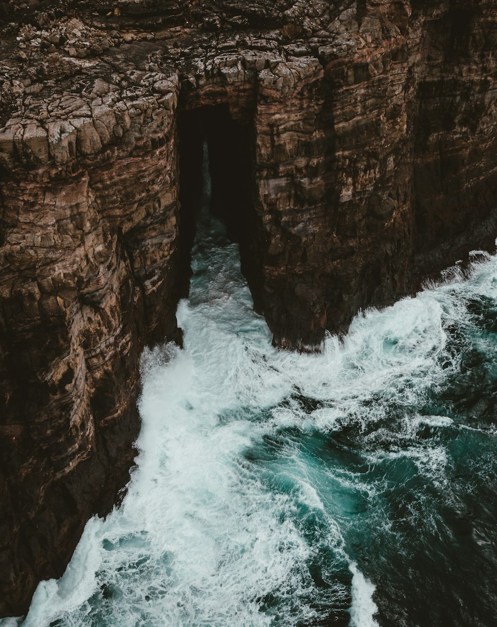 waves crashing on brown mountain