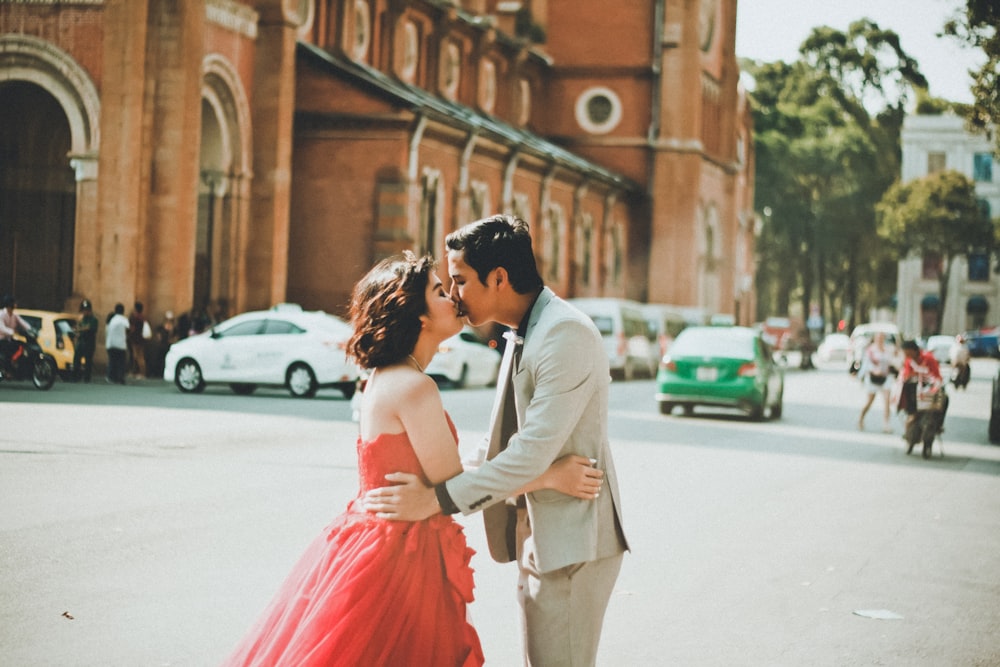 couple kissing on street near building during daytime