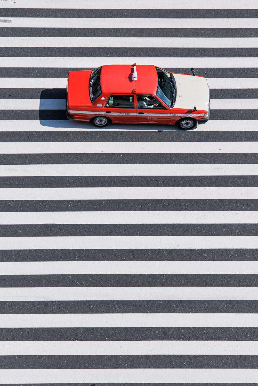 sedã vermelho e branco passando na faixa de pedestres