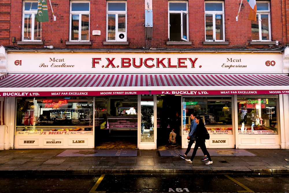 man and woman walking in front of F.X. Buckley store