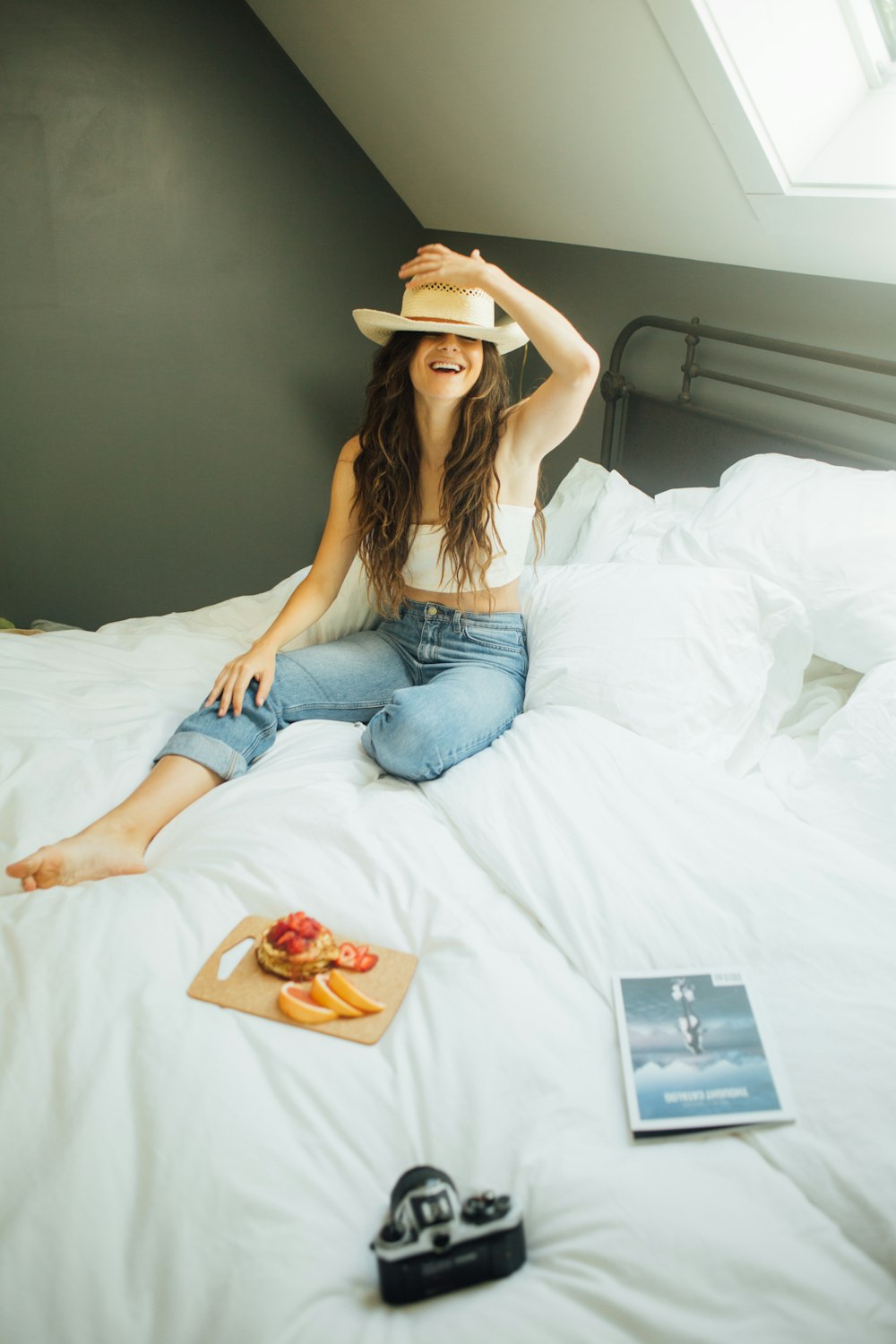 woman sitting on bed holding her hat