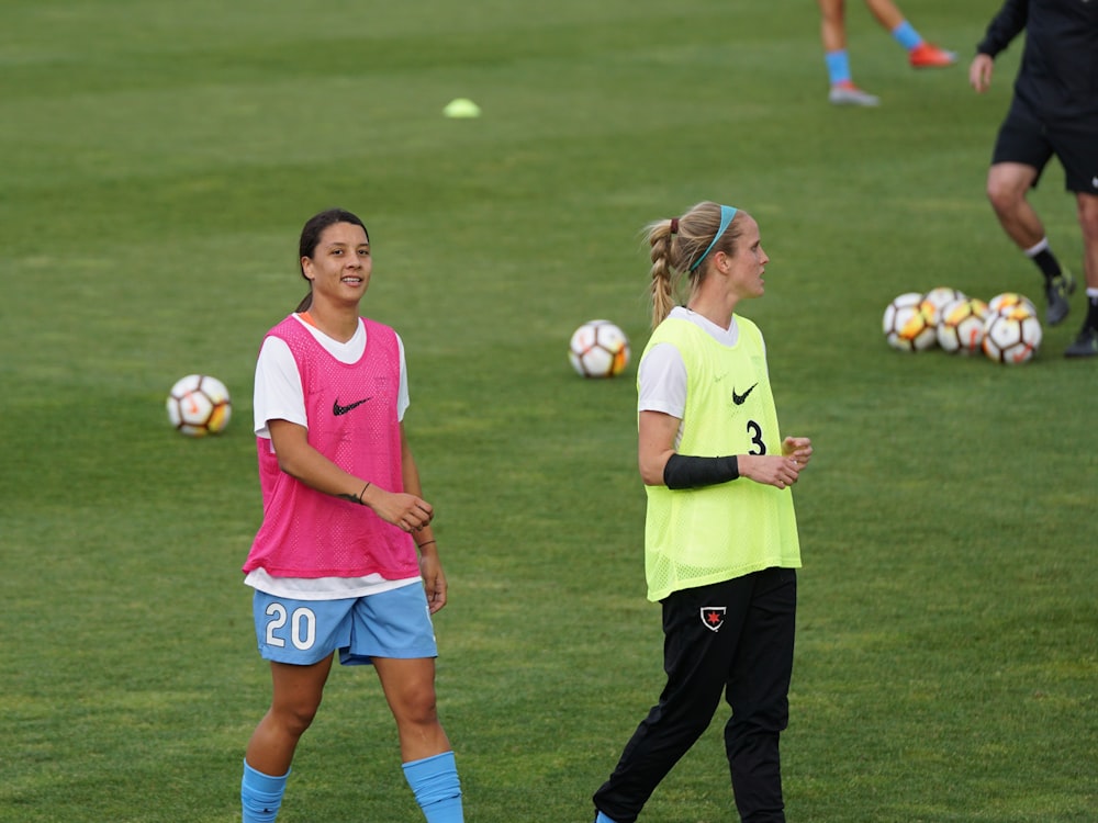 dos mujeres con camisetas sin mangas Nike rosas y amarillas