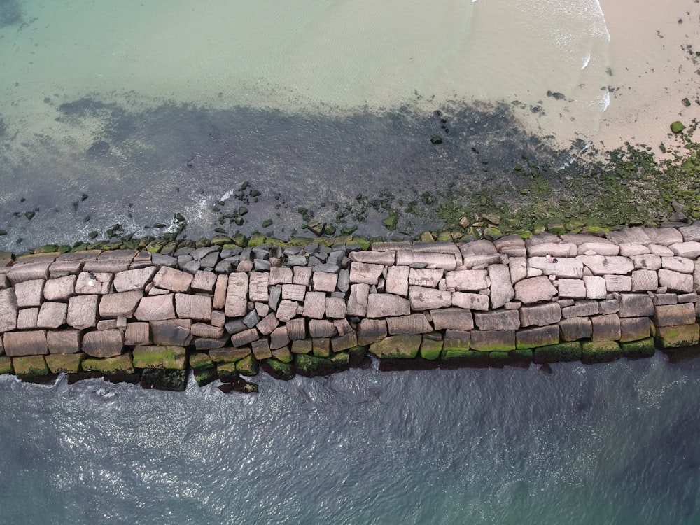 parede de tijolo de concreto cinza ao lado do corpo de água durante o dia