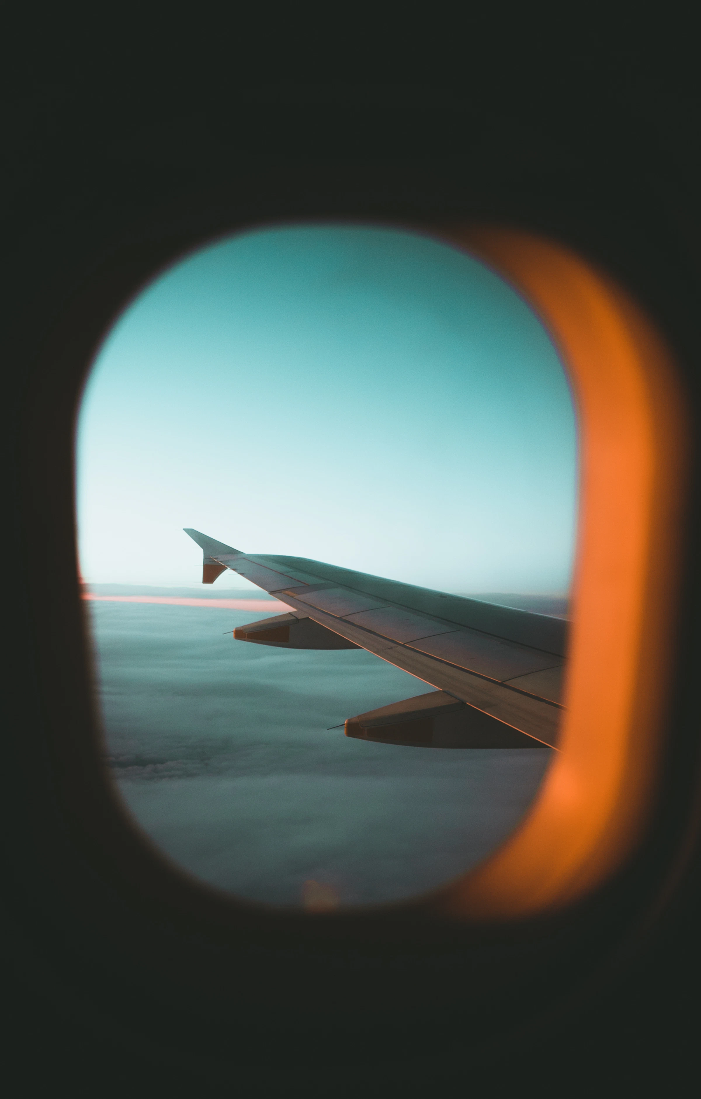 Airplane wing above the clouds at sunset