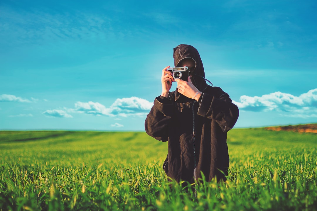 person taking photo using camera in green field