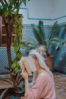 woman sitting on chair while reading book in a moroccan riad