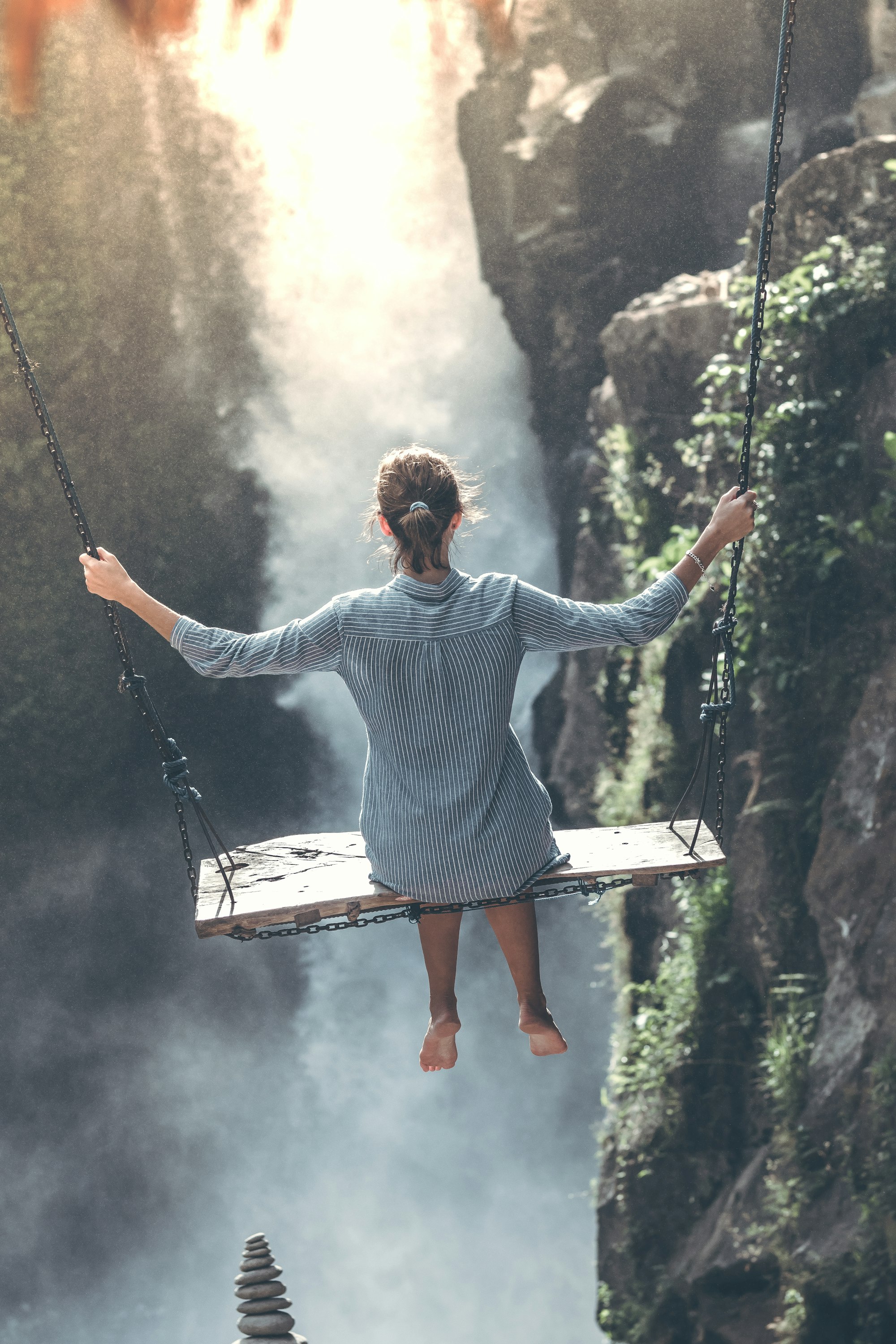 Beautiful woman swings near waterfall