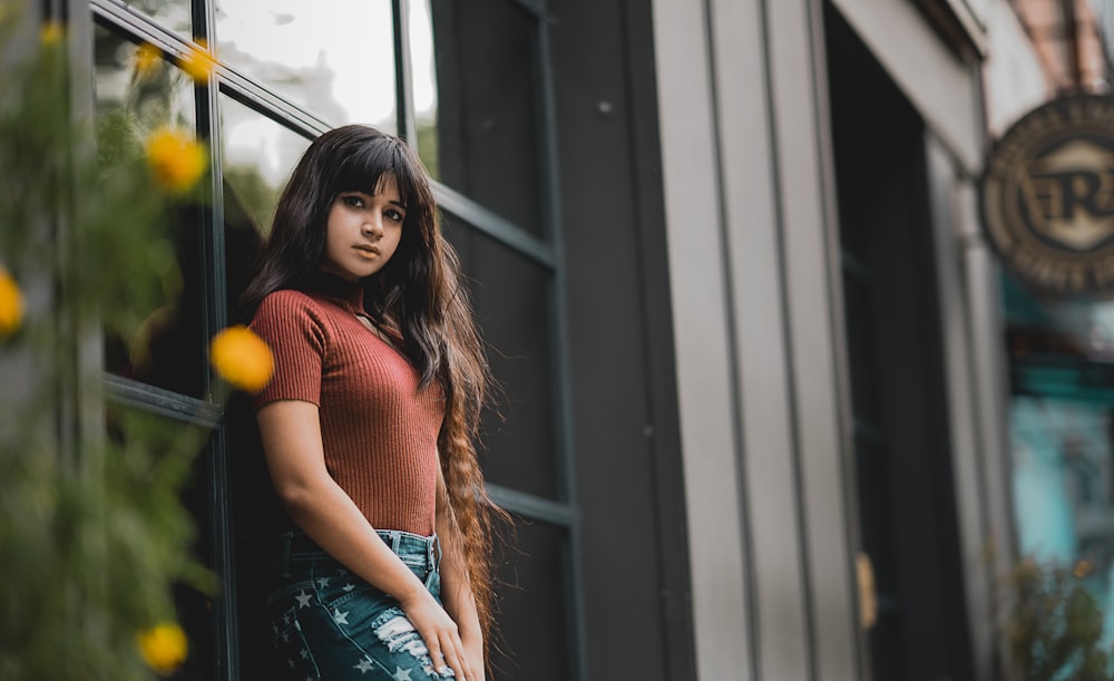 woman leaning on glass window outdoor during daytime