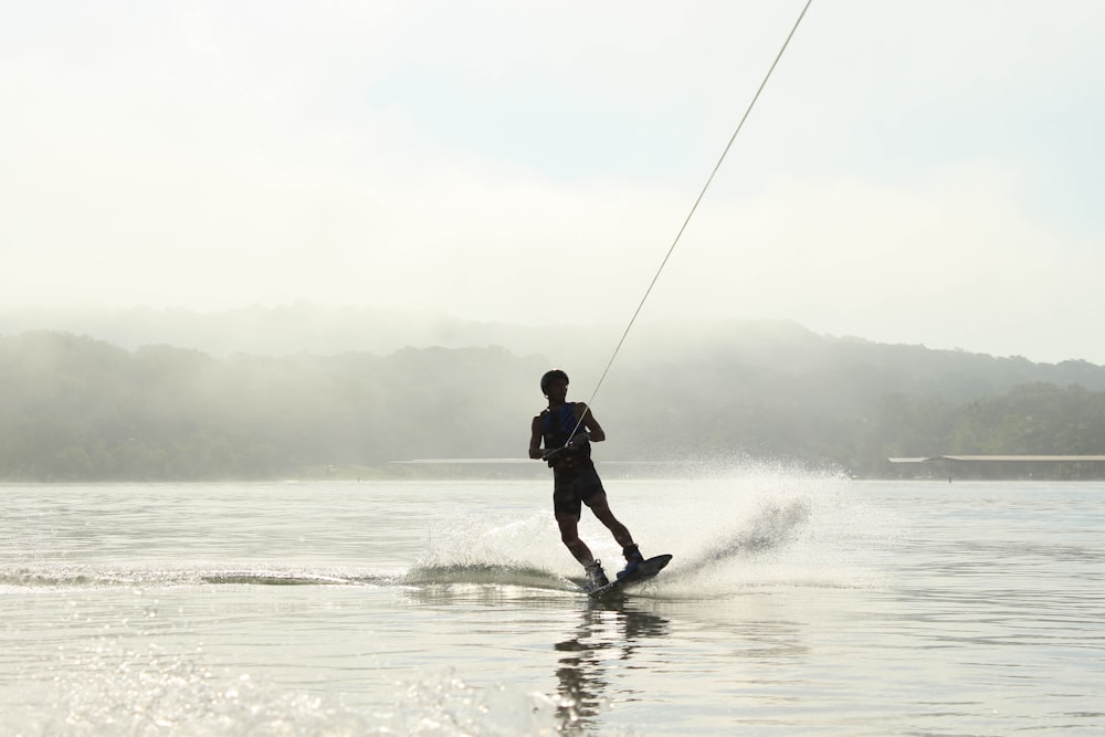 Foto eines Mannes, der auf einem Gewässer surft und ein Seil hält
