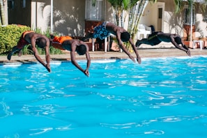 four men diving to the pool
