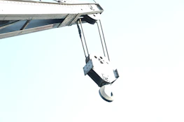Close-up of a powerful crane hook holding a heavy load with a clear blue sky background.