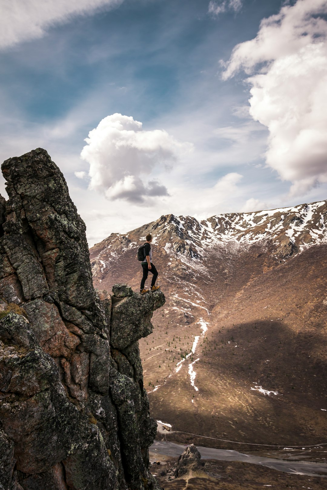 man standing on rock facing mountains