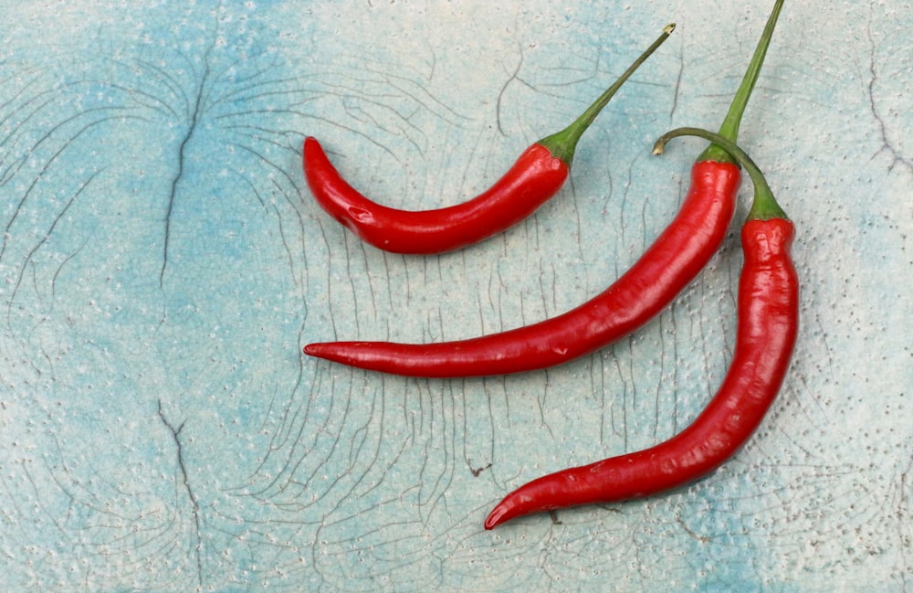 three red chili on gray surface