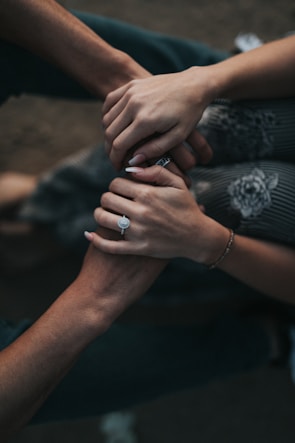 Close-up of intertwined hands with wedding rings, capturing a tender moment.