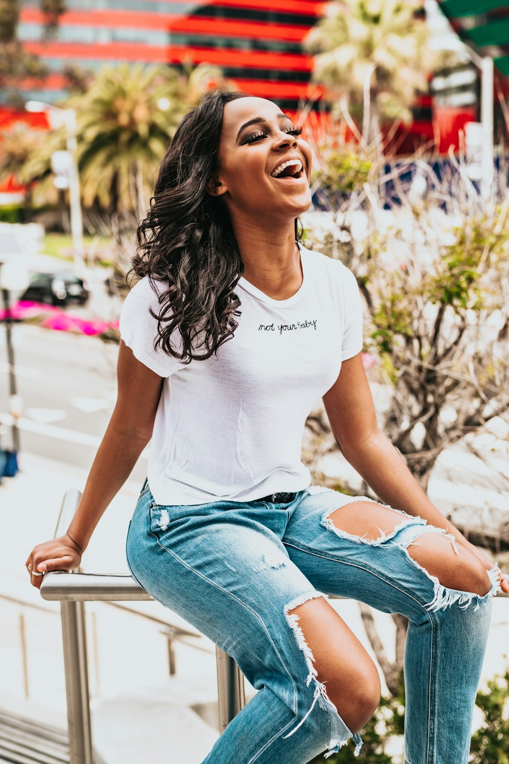 girl sitting on metal hand rail while laughing