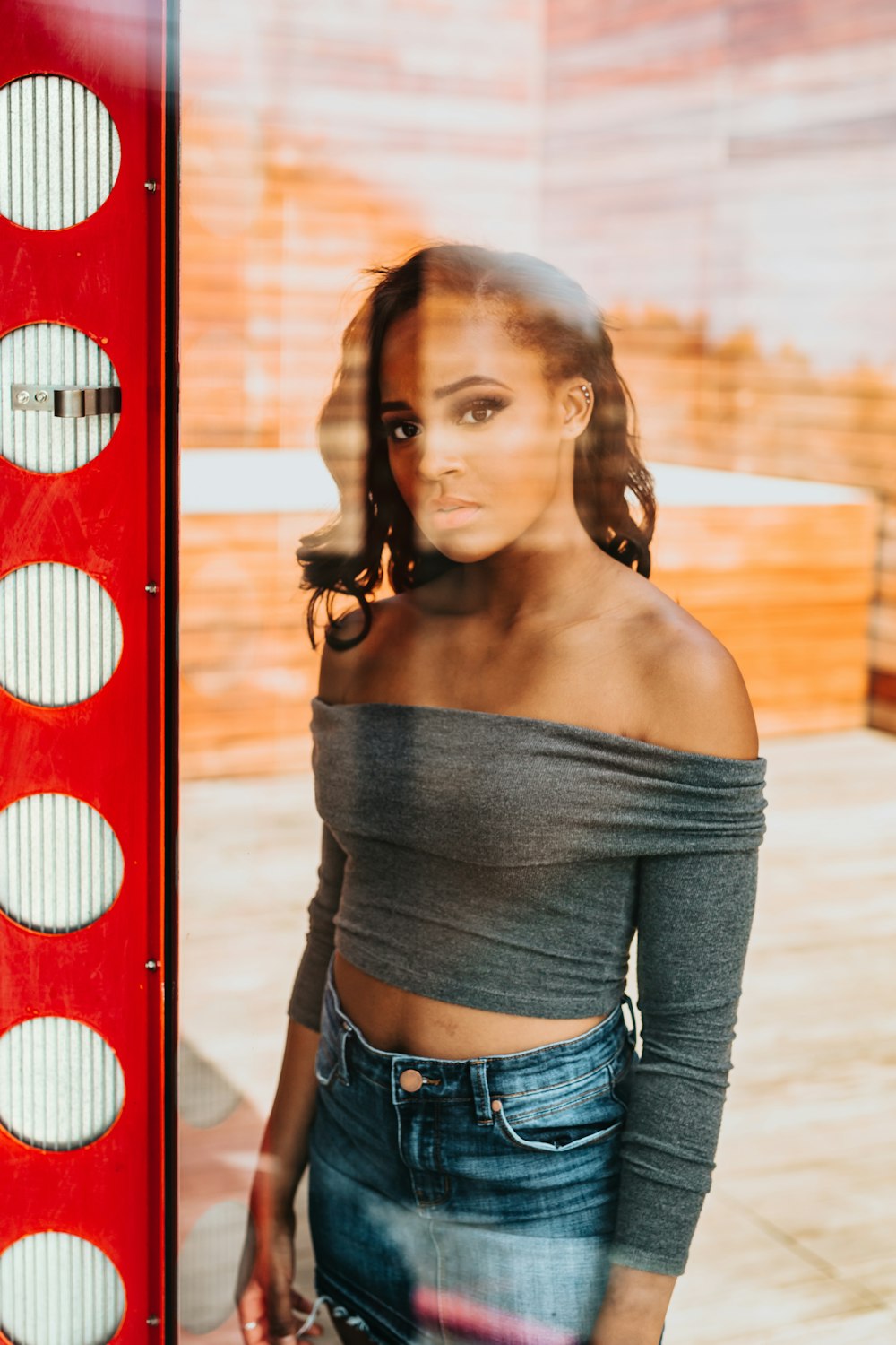 standing woman black off-shoulder shirt and blue denim jeans