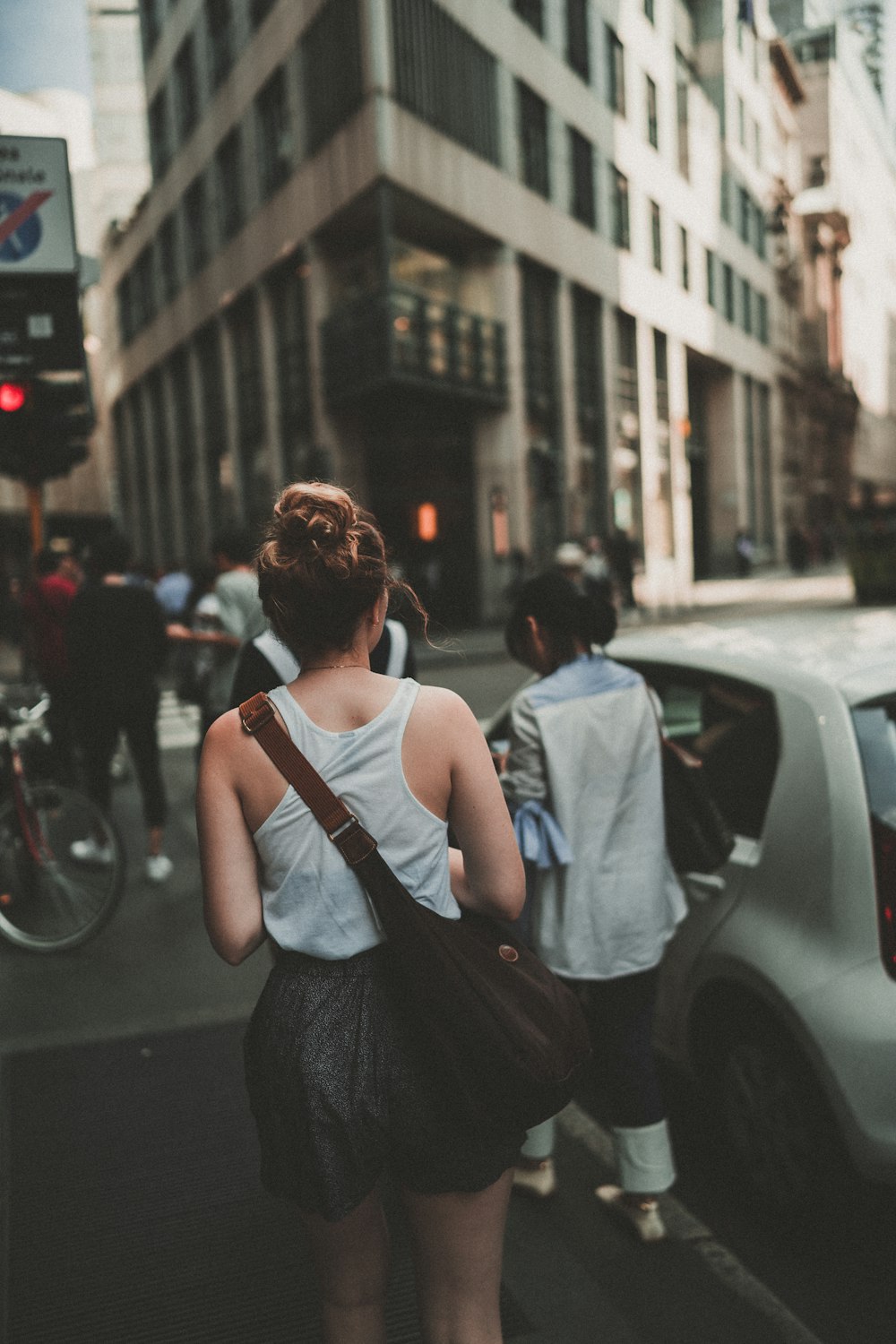 woman carrying brown leather bag while walking on road