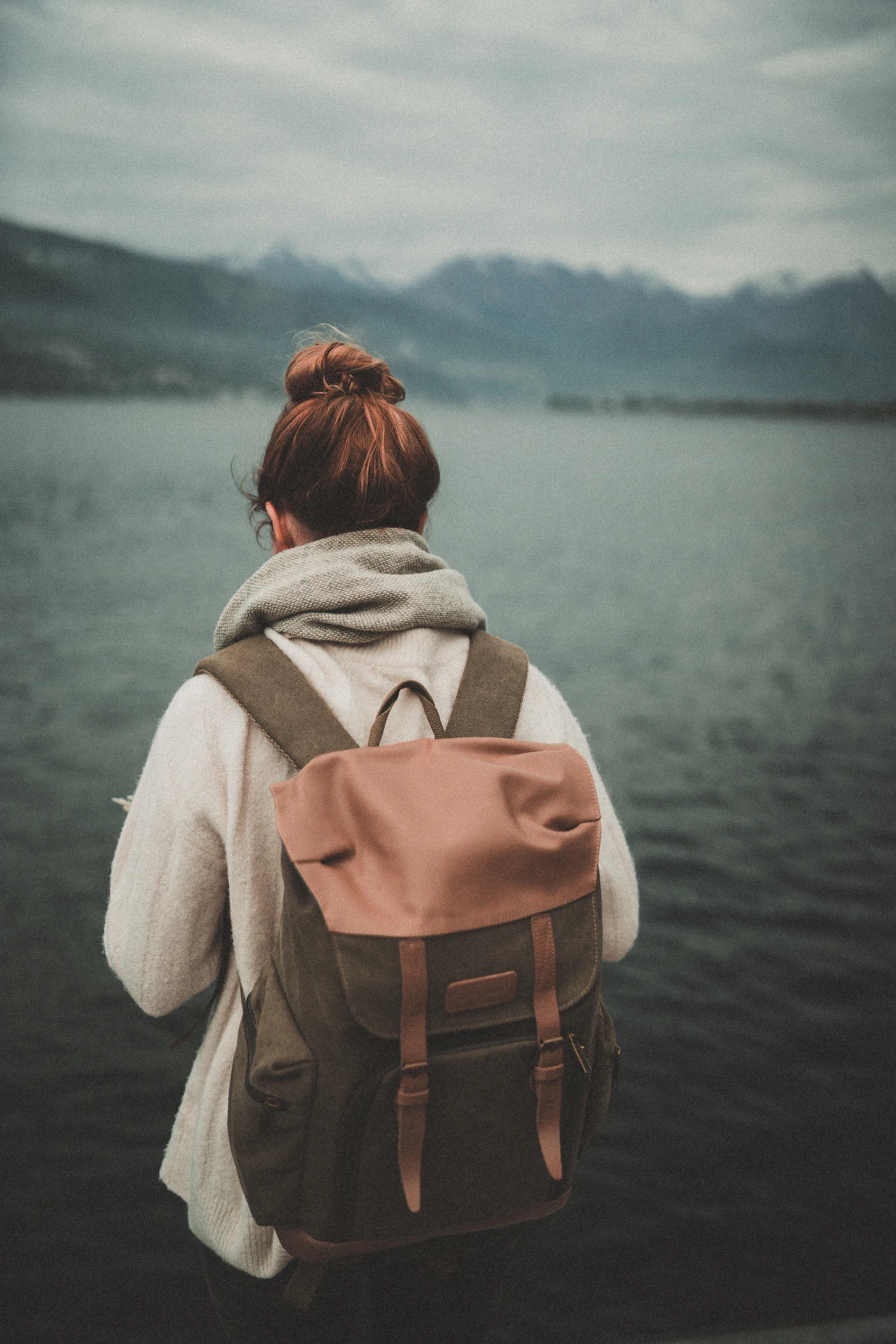 Person mit Rucksack blickt auf einen ruhigen See