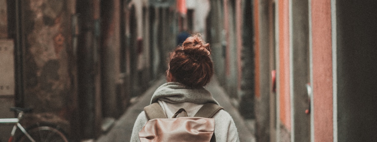 woman walking on street surrounded by buildings