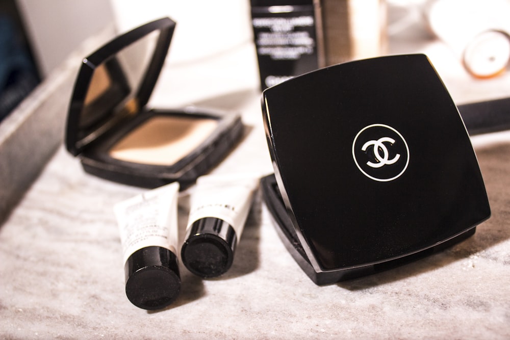 women's Chanel pressed powder beside tube bottles