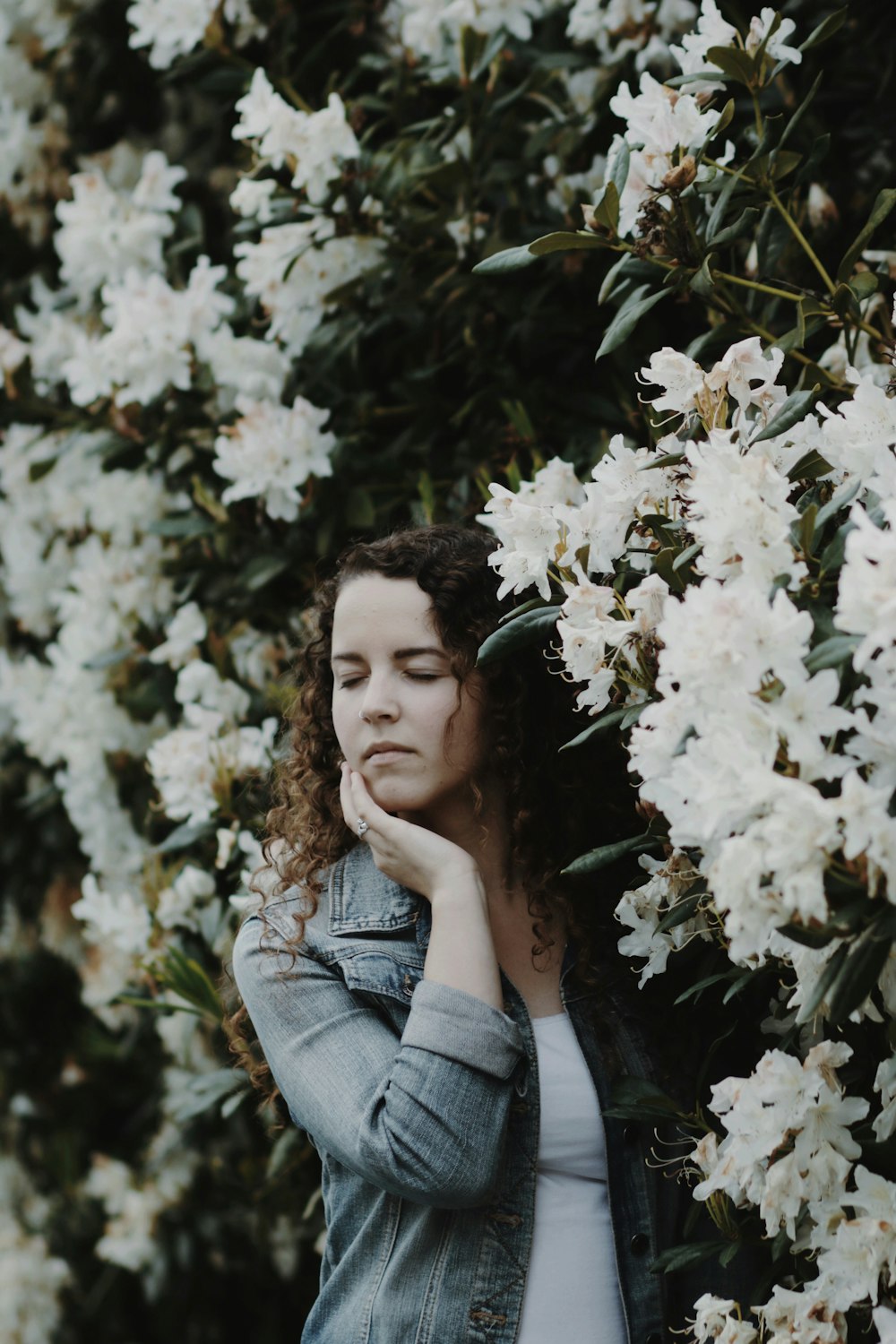 woman touching face with her right hand with white flowers on background