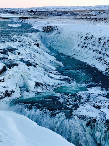 A breathtaking view of Iceland's rugged landscape with a waterfall cascading into a crystal-clear river.