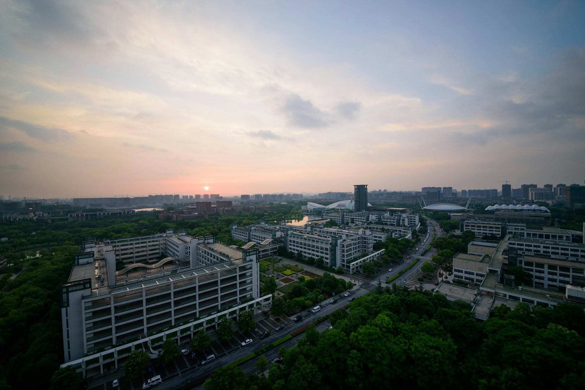 An aerial view of a sprawling urban development project captured at sunset, showcasing the blend of nature and modern infrastructure.