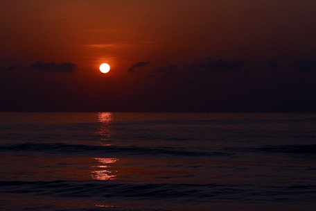 A peaceful horizon where the sun dips below the sea, casting a soft glow over the water.