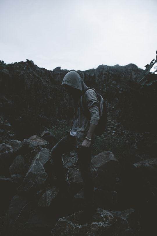 man in hoodie stepping on rocks in Los Algarrobos Panama