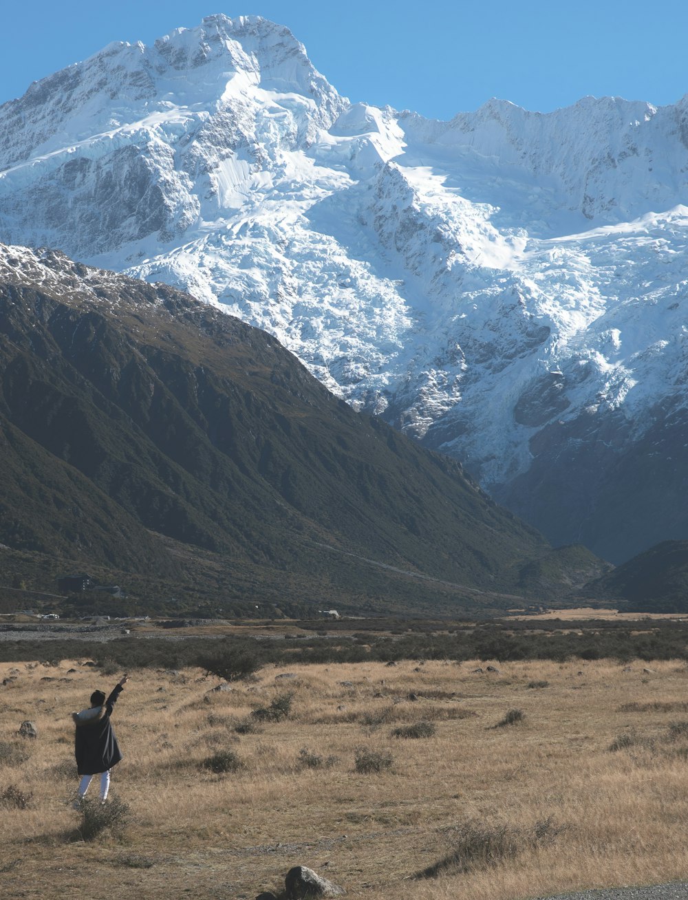 person in black jacket standing at the bottom of the mountain