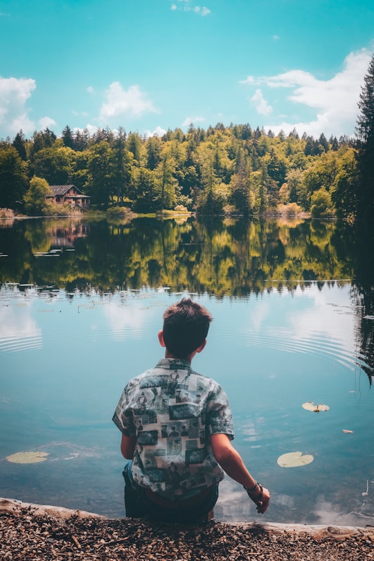 man sitting in front of pond under blue sky in Lago di Cei Italy