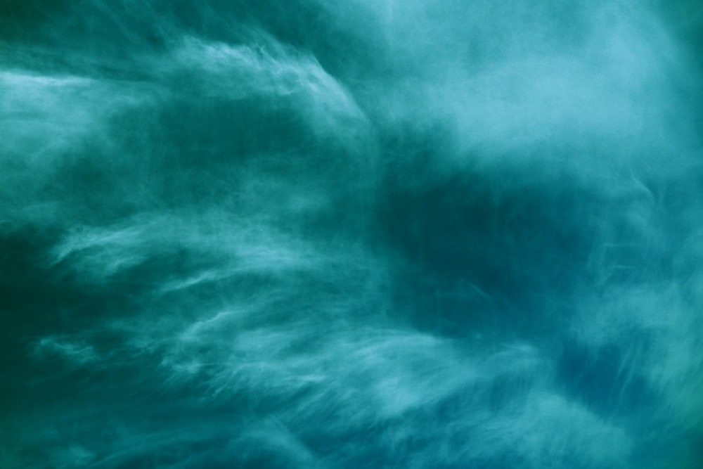 a plane flying through a cloudy blue sky