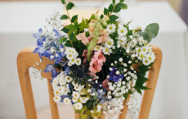 white petaled flowers on brown wooden armless chair