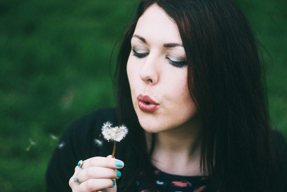 woman blowing white dandelion