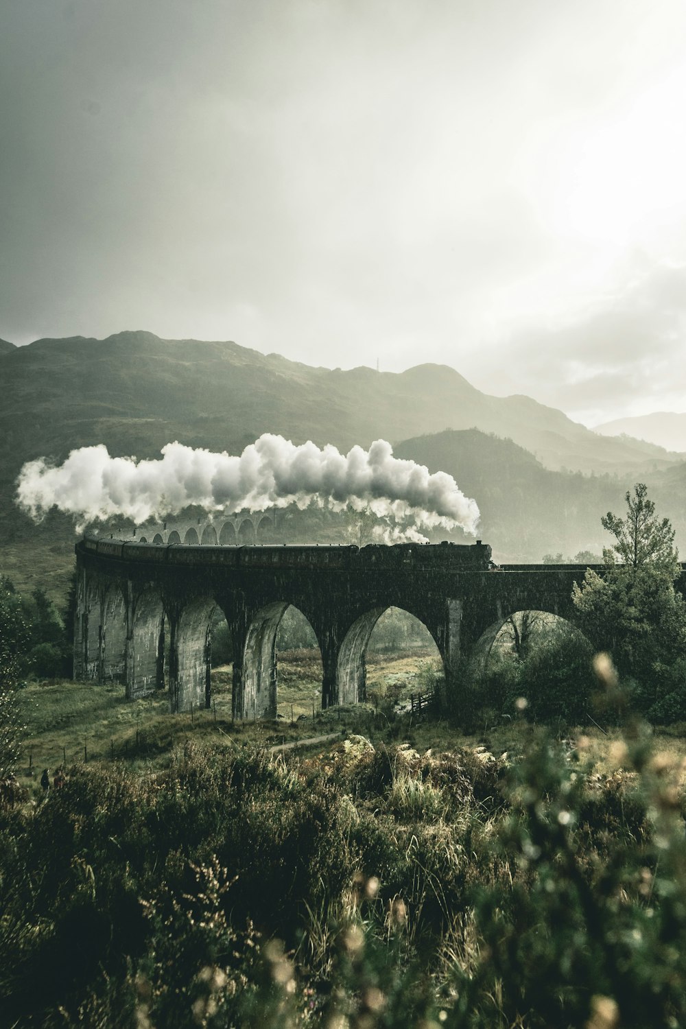 Train noir sur un pont de chemin de fer sous de lourds nuages