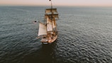 brown sailboat in beach under white sky