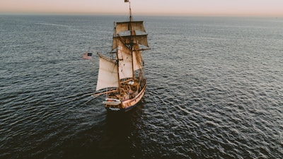 brown sailboat in beach under white sky