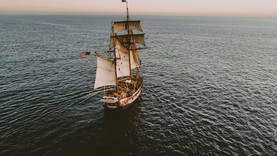 brown sailboat in beach under white sky