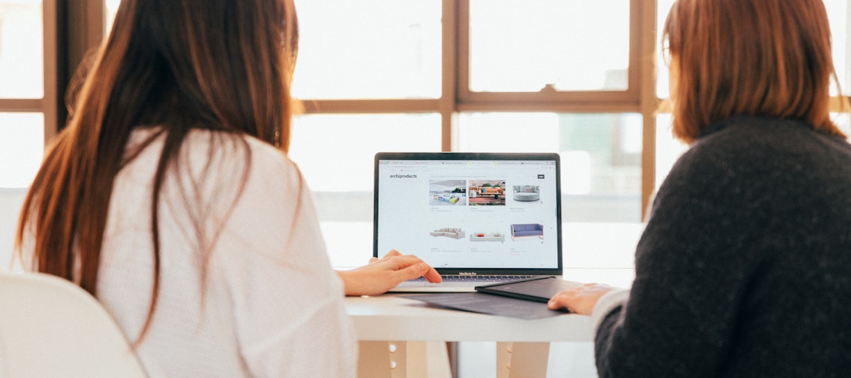 two women talking while looking at laptop computer