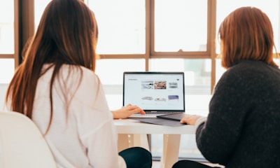 two women talking while looking at laptop computer