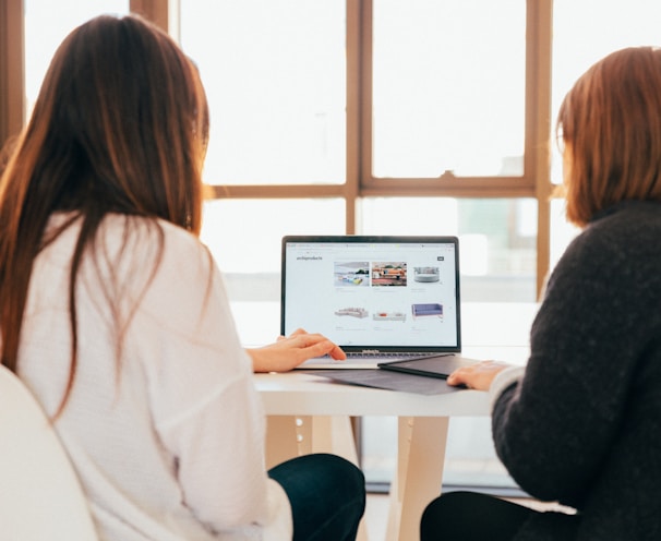 two women talking while looking at laptop computer