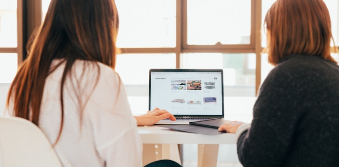 two women talking while looking at laptop computer