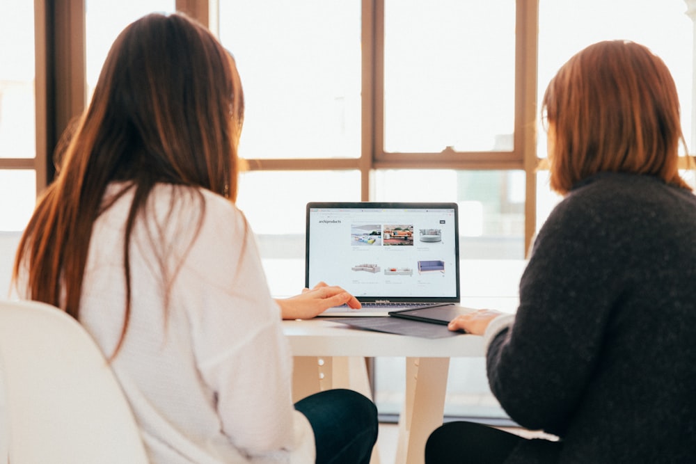Dos mujeres hablando mientras miran una computadora portátil