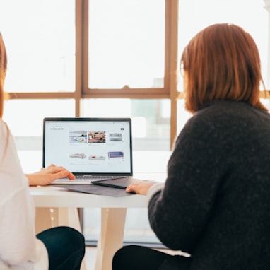 two women talking while looking at laptop computer