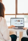 two women talking while looking at laptop computer