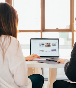 two women talking while looking at laptop computer