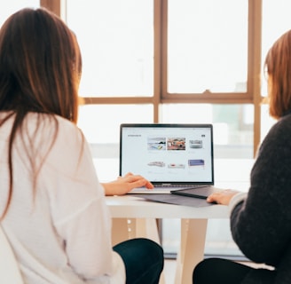 two women talking while looking at laptop computer